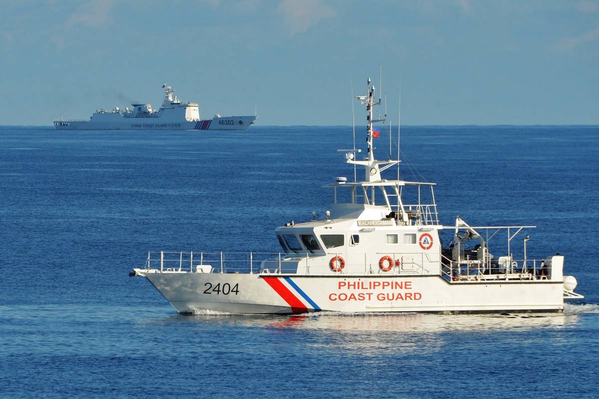 (FILES) This file photo taken on May 14, 2019 shows a Philippines' coast guard ship (R) sailing past a Chinese coast guard ship during a joint search and rescue exercise between the Philippines and US coast guards near Scarborough Shoal in the South China Sea. - The Scarborough Shoal fishing ground, tapped by generations of Filipino fishermen, is one of many potential flashpoints for military conflict over the South China Sea. China and Taiwan both claim sovereignty over almost the entire sea, while the Philippines, Vietnam, Malaysia and Brunei have competing claims to parts of it. (Photo by Ted ALJIBE / AFP) / TO GO WITH China-Xi-congress-Philippines-fishing, FOCUS by Allison JACKSON