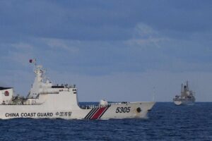A Chinese Coast Guard ship sails near a Philippine vessel (R) that was part of a convoy of civilian boats in the disputed South China Sea on December 10, 2023. A convoy of civilian boats planning to deliver provisions to Filipino fishermen and troops in the disputed South China Sea aborted the trip on December 10 after 'constant shadowing' by Chinese vessels, the organiser said. TED ALJIBE / AFP