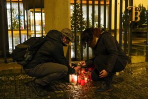 SMALL SHRINE A man assists a woman in lighting a candle outside the building of the Philosophical Faculty of Charles University in downtown Prague, Czech Republic, following a mass shooting there on Thursday, Dec. 21, 2023. AP PHOTO