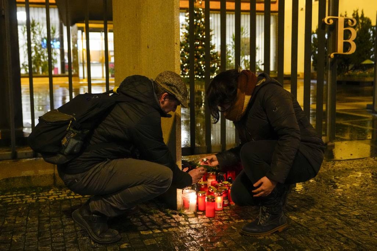 SMALL SHRINE A man assists a woman in lighting a candle outside the building of the Philosophical Faculty of Charles University in downtown Prague, Czech Republic, following a mass shooting there on Thursday, Dec. 21, 2023. AP PHOTO