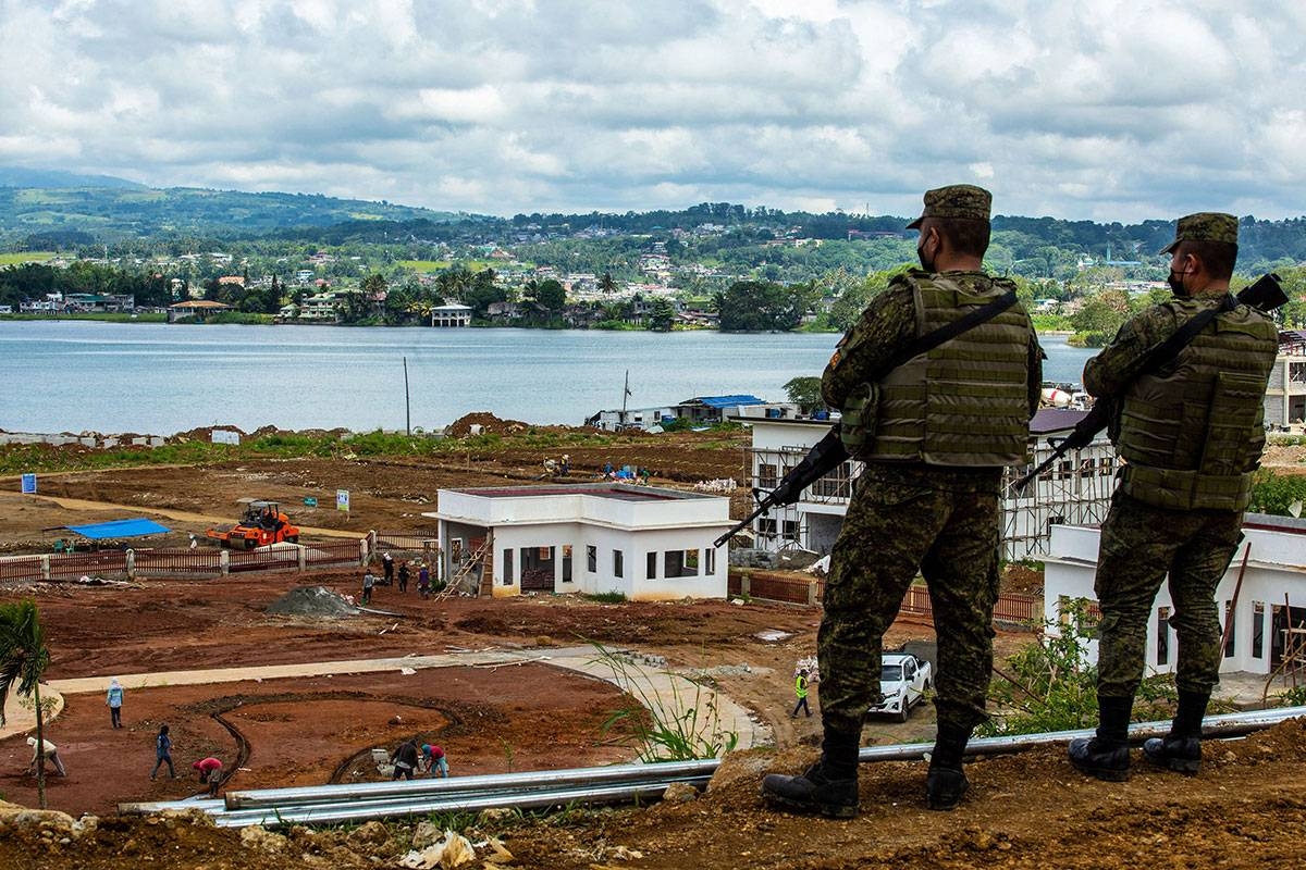 This photo taken on May 23, 2021 shows Philippine soldiers looking over workers constructing a building which was a main battleground in 2017 when Islamic State-inspired Muslim militants laid siege to the southern Philippine city of Marawi, resulting in a five-month campaign that claimed more than 1,000 lives until government troops re-took control. Ferdinandh CABRERA / AFP