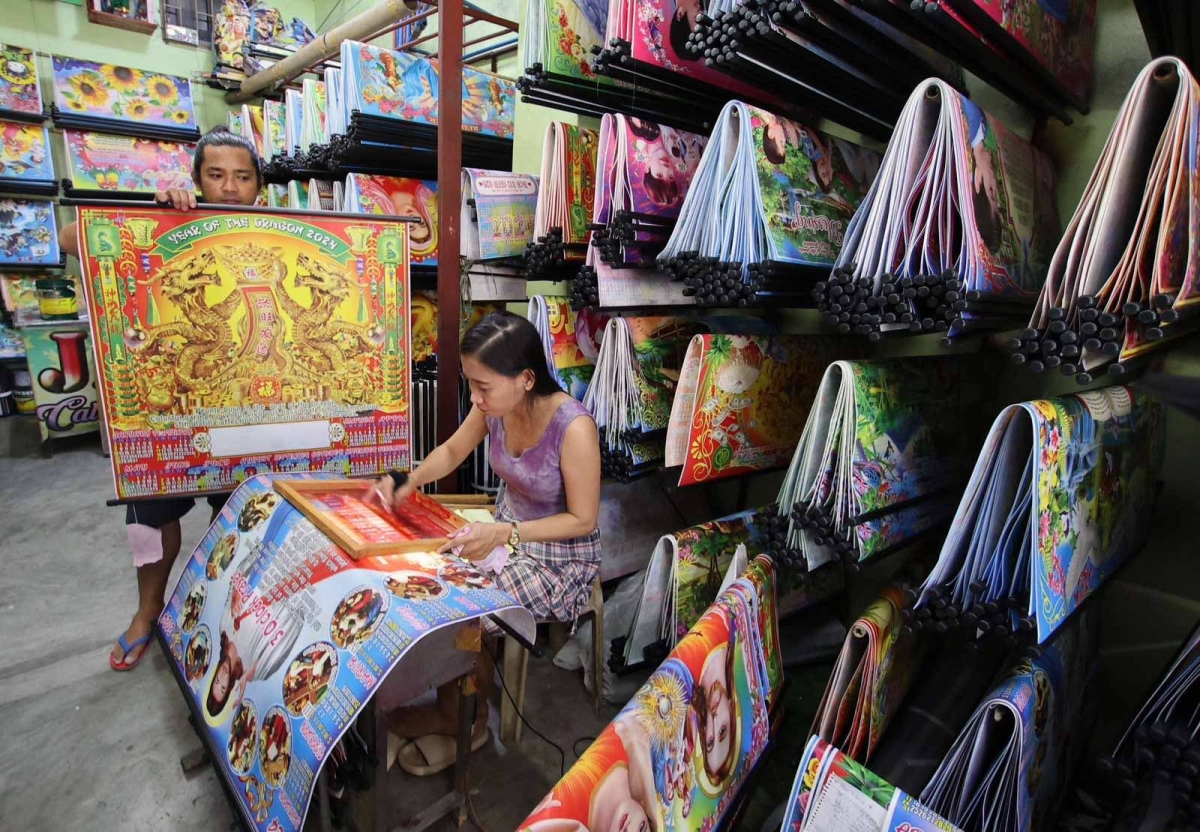 A customer chooses a calendar design at a printing shop along Commonwealth Avenue in Quezon City on Wednesday, Dec. 27, 2023. PHOTO BY MIKE DE JUAN