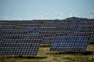 This photograph shows photovoltaic solar panels and windmills in the background around the Spanish Navarre town of Milagro on April 5, 2023. Spain generated record 50% of power from renewables in 2023, AFP reports on January 4, 2024. ANDER GILLENEA / AFP