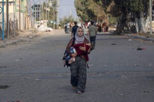 A woman carries a child while heading toward southern Gaza. UNICEF/Eyad El Baba