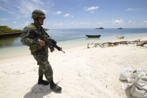 This photo shows a Philippine soldier Tychico Octobre patrols a beach in Pagasa Island (Thitu Island) at the Spratly group of islands in the South China Sea, west of Palawan, on May 11, 2015. AFP PHOTO / POOL / RITCHIE B. TONGO
