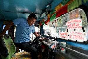 This photo taken on January 15, 2024 shows a man gets in the driver's seat of his jeepney at a terminal in Manila. Philippine jeepney drivers staged a noisy protest in the capital Manila on January 16, 2024 over the government's plan to phase out the smoke-belching vehicles nationwide and replace them with modern mini-buses. JAM STA ROSA / AFP
