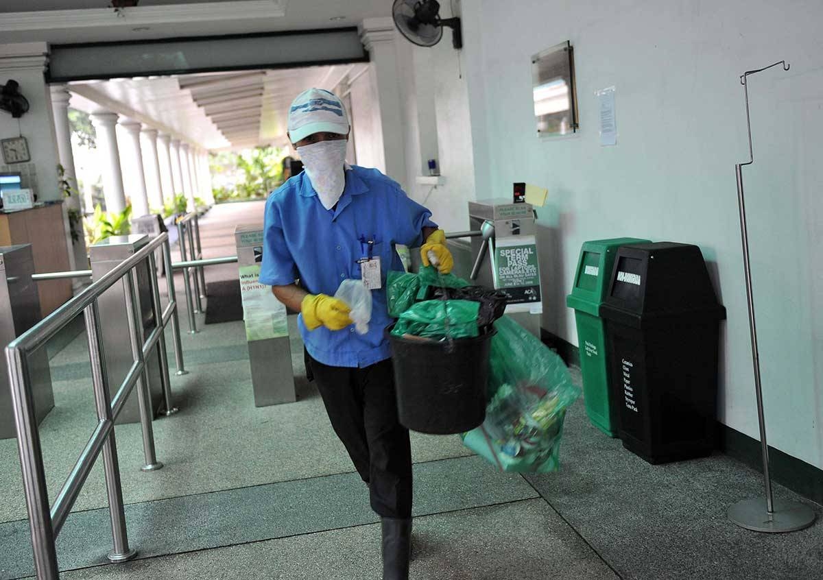 A worker wearing mask collects waste from a dust bin. AFP File Photo
