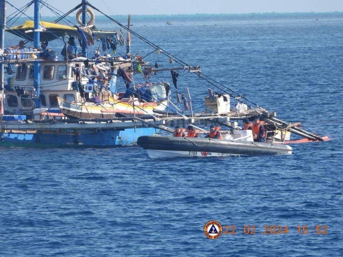 This handout photo taken on February 22, 2024 and received on February 25, 2024 from the Philippine Coast Guard shows China Coast Guard personnel onboard a rigid-hulled inflatable boat (right) as they shadow a Philippine fishing boat (left) during the Philippine Bureau of Fisheries and Aquatic Resources (BFAR) mission to bring supplies to fishermen near the China-controlled Scarborough Shoal in the disputed South China Sea. AFP PHOTO / Philippine Coast Guard