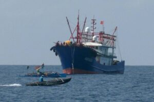 This photo taken on February 6, 2023 shows Filipino fishermen aboard their boats sailing past a Chinese vessel in the Scarborough Shoal, in the disputed South China Sea. STR / AFP