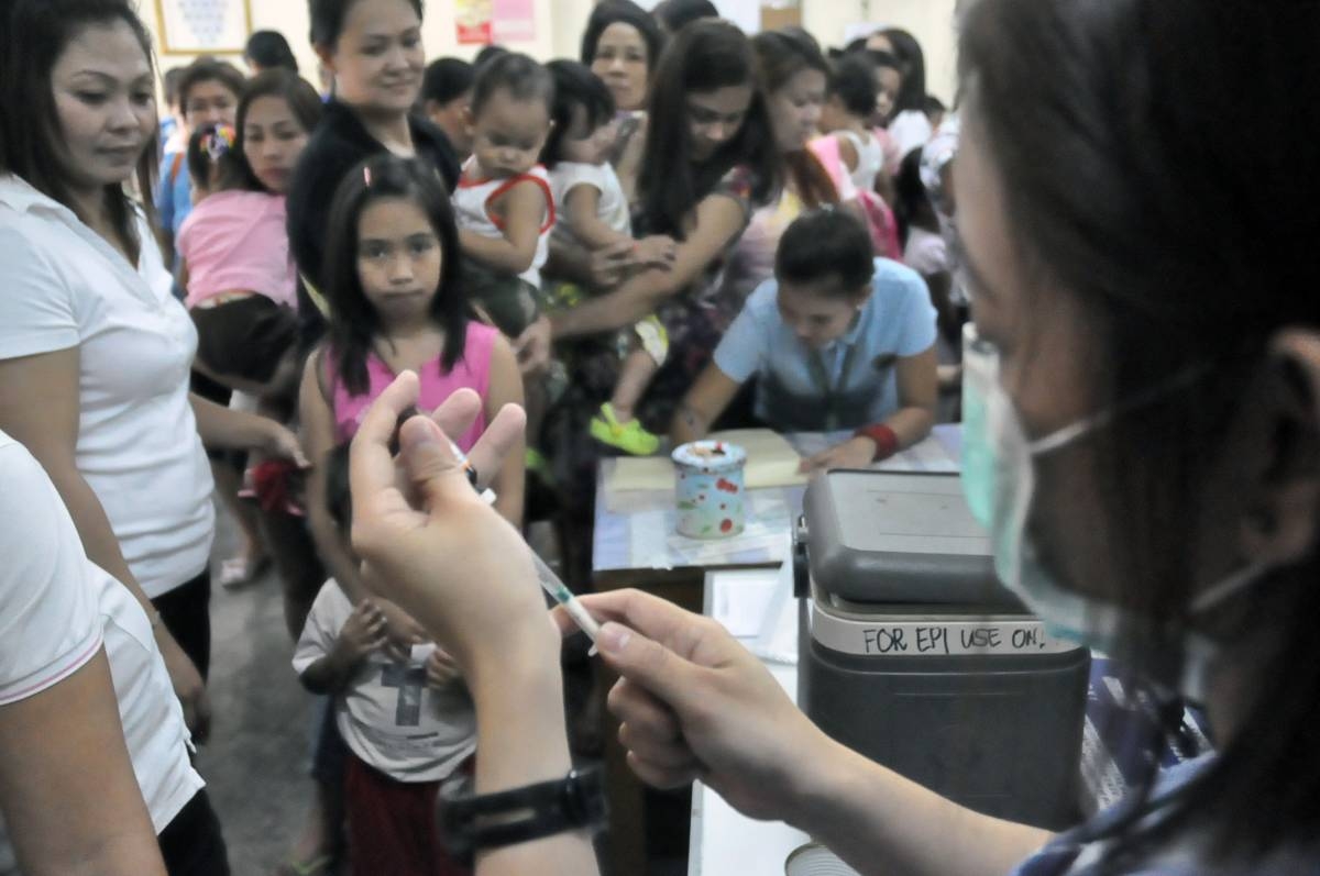 PHOTO BY : EDWIN MULI
Mothers with their infants line up while a head nurse prepares a syringe during free anti-measles vaccination inside the Marulas Puericulture Center in Valenzuela City on Wednesday. Parents heed on the Department of Health (DOH) call on immediate free measles vaccination after an outbreak where thousands are afftected by the viral disease and nearly a hundred reported dead.