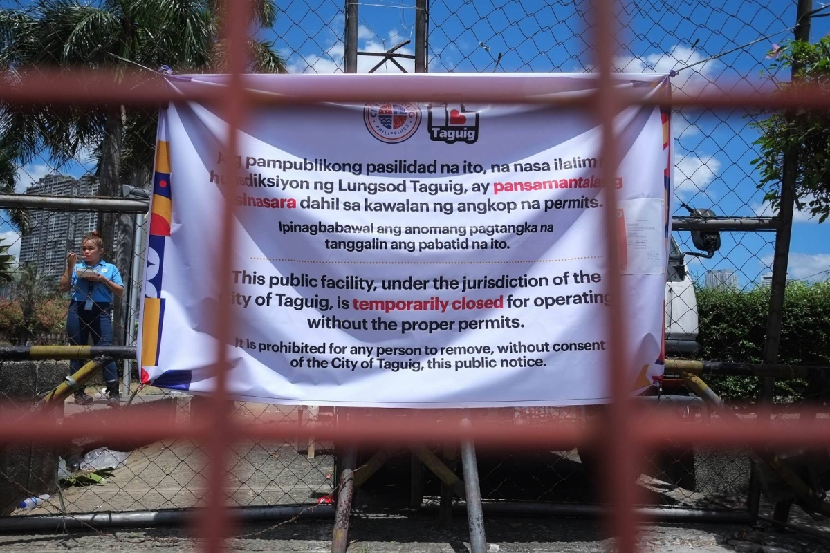 Taguig personnel padlock the Makati Park and Garden in West Rembo, Taguig City, Sunday. Makati City personnel are still seen inside the park while Taguig police and other Taguig LGU personnel are situated outside the park. PHOTOS BY J. GERARD SEGUIA