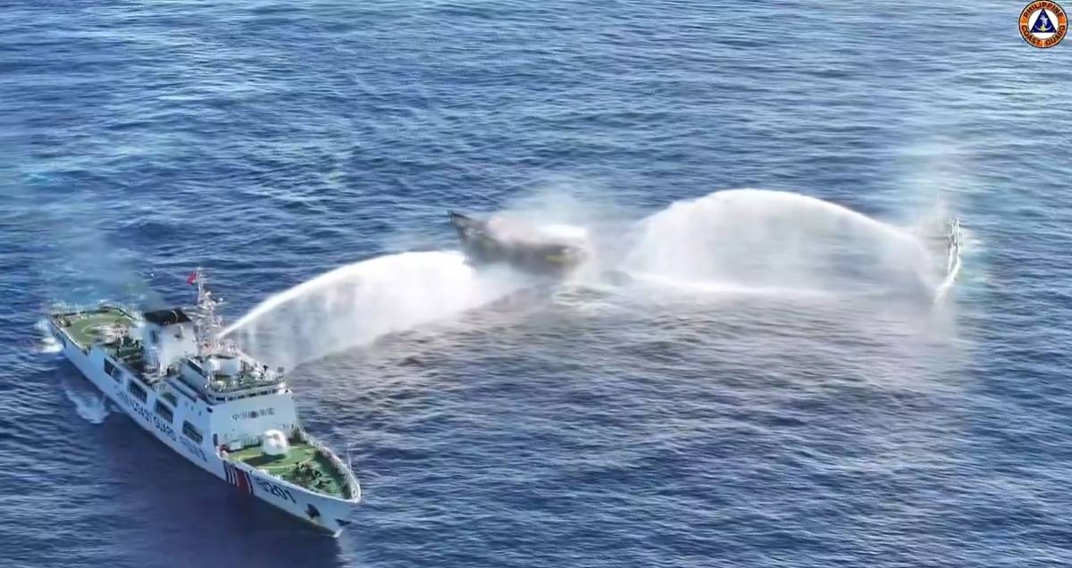 In this frame grab from aerial video footage taken on March 5, 2024 and released by the Philippine Coast Guard (PCG), Chinese Coast Guard ships (L and R) deploy water cannons at the Philippine military-chartered civilian boat Unaizah May 4 (C) during its supply mission near Second Thomas Shoal in the disputed South China Sea. The Philippines said on March 5 that China Coast Guard vessels caused two collisions with Philippine vessels and water cannoned a boat, leaving four crew injured during a resupply mission in the South China Sea. (Photo by Handout / Philippine Coast Guard (PCG) / AFP)
