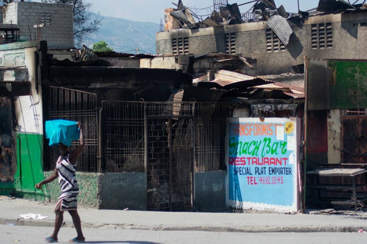 A woman walks past a drugstore burned by gang members during a protest in Port-au-Prince, Haiti, on March 12, 2024. AFP PHOTO