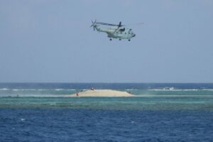 This handout photo taken on March 23, 2024 and received from the Philippine Bureau of Fisheries and Aquatic Resources (PCG/BFAR) on March 25, 2024 shows a Chinese helicopter hovering as Philippine scientists inspect a cay near the Philippine-held Thitu Island, in Spratly Islands, in the disputed South China Sea. AFP PHOTO /PHILIPPINE COAST GUARD/BUREAU OF FISHERIES AND AQUATIC RESOURCES (PCG/BFAR)