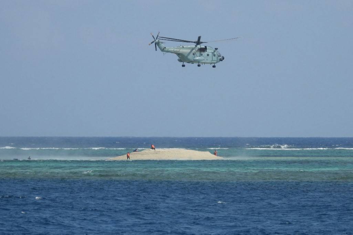 This handout photo taken on March 23, 2024 and received from the Philippine Bureau of Fisheries and Aquatic Resources (PCG/BFAR) on March 25, 2024 shows a Chinese helicopter hovering as Philippine scientists inspect a cay near the Philippine-held Thitu Island, in Spratly Islands, in the disputed South China Sea. AFP PHOTO /PHILIPPINE COAST GUARD/BUREAU OF FISHERIES AND AQUATIC RESOURCES (PCG/BFAR)