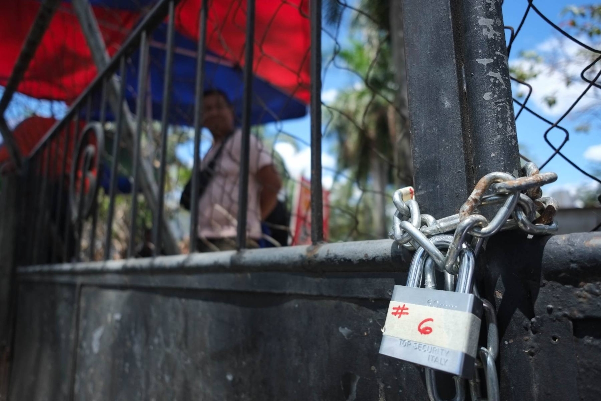 Taguig personnel padlock the Makati Park and Garden in West Rembo, Taguig City, Sunday. Makati City personnel are still seen inside the park while Taguig police and other Taguig LGU personnel are situated outside the park. FILE PHOTO BY J. GERARD SEGUIA