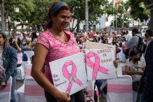 A woman shows placards with draws of pink ribbons as she attends an event organized by the Women's Ministry to commemorate the International Day of the fight against breast cancer at the Bolivar square in the historic center in Caracas on October 19, 2022. (Photo by Yuri CORTEZ / AFP)