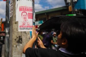 Members of Akbayan Youth put up posters calling for the arrest of Pastor Apollo Quiboloy in Quezon City on Monday, March 18, 2024. PHOTOS BY JOHN ORVEN VERDOTE