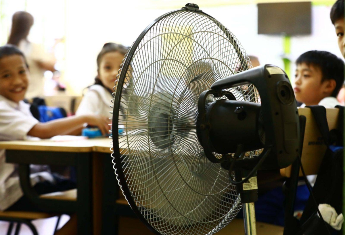 Students of the Justo Lukban Elementary School in Paco, Manila on Tuesday, April 2, 2024, gather near electric fans to cool themselves while in class. PHOTOS BY MIKE ALQUINTO