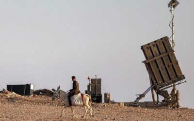 A boy rides a donkey near one of the batteries of Israel's Iron Dome missile defence system at a village not recognised by Israeli authorities in the southern Negev desert on April 14, 2024. AHMAD GHARABLI / AFP