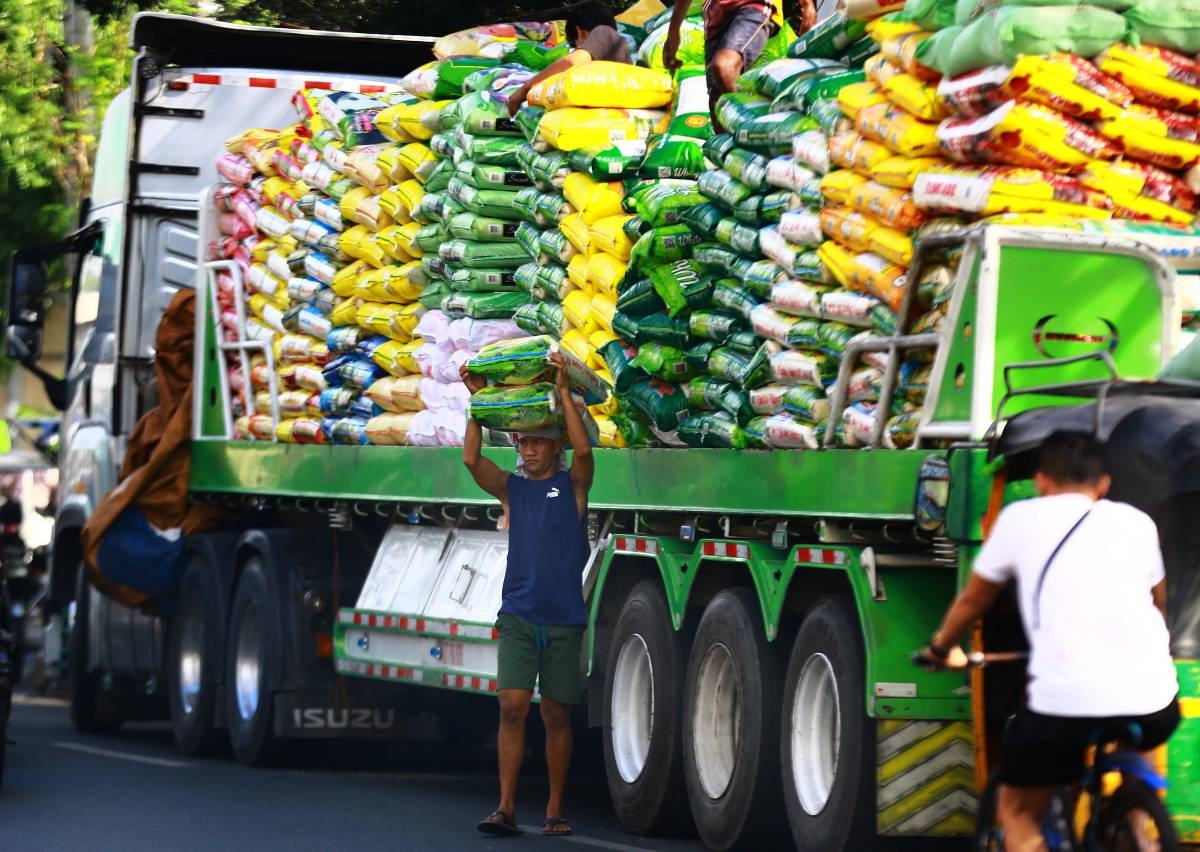 Workers unload sacks of rice from a delivery truck in Tondo, Manila on January 22, 2024. PHOTO BY MIKE ALQUINTO