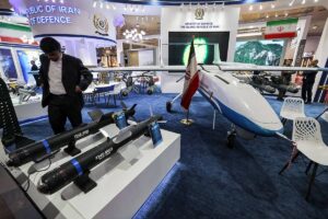A man stands by Iran's F-365-NO13 and F-345-NO22 smart bombs on display at the 2024 International Defence Exhibition Iraq (IQDEX) in Baghdad on April 21, 2024. AHMAD AL-RUBAYE / AFP