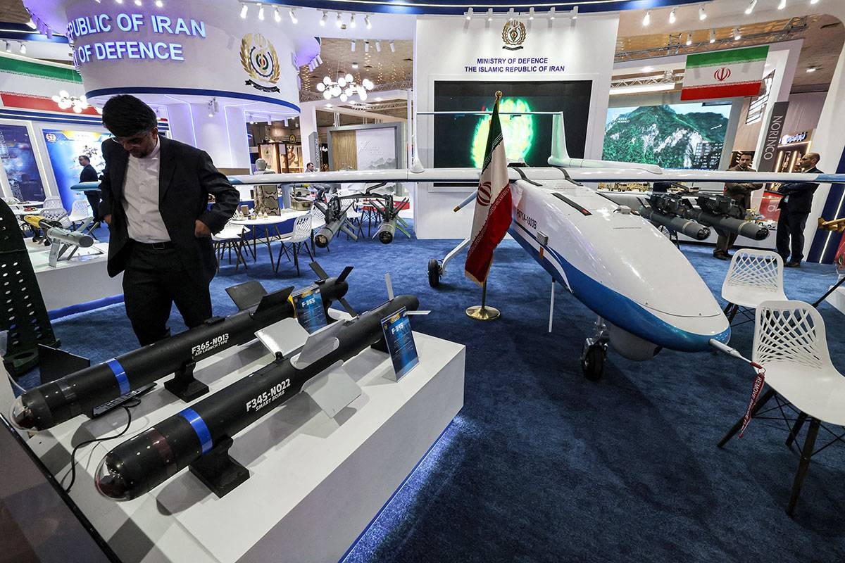 A man stands by Iran's F-365-NO13 and F-345-NO22 smart bombs on display at the 2024 International Defence Exhibition Iraq (IQDEX) in Baghdad on April 21, 2024. AHMAD AL-RUBAYE / AFP