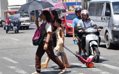 A family holding umbrellas to protect themselves from the sun walk across a street in Manila on April 25, 2024. Extreme heat is scorching parts of South and Southeast Asia, prompting health warnings from authorities as high temperatures are recorded across the region. Ted ALJIBE / AFP