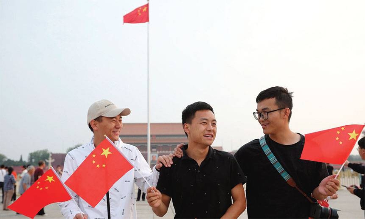 Three men hold Chinese national flags at Tiananmen Square in Beijing on Tuesday after the flag-raising ceremony. GLOBAL TIMES PHOTO