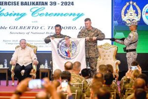 FURLING THE FLAG Philippine Army Maj. Gen. and Balikatan Director Marvin Licudine (second from left) and Commander of the US First Marine Expeditionary Force Lt. Gen. Michael Cederholm (second from right) furl the Balikatan (shoulder-to-shoulder) flag during the closing ceremony of the US-Philippines Balikatan joint military exercise at Camp Aguinaldo in Quezon City on May 10, 2024. Also in photo is Defense Secretary Gilbert Teodoro. JAM STA ROSA / AFP