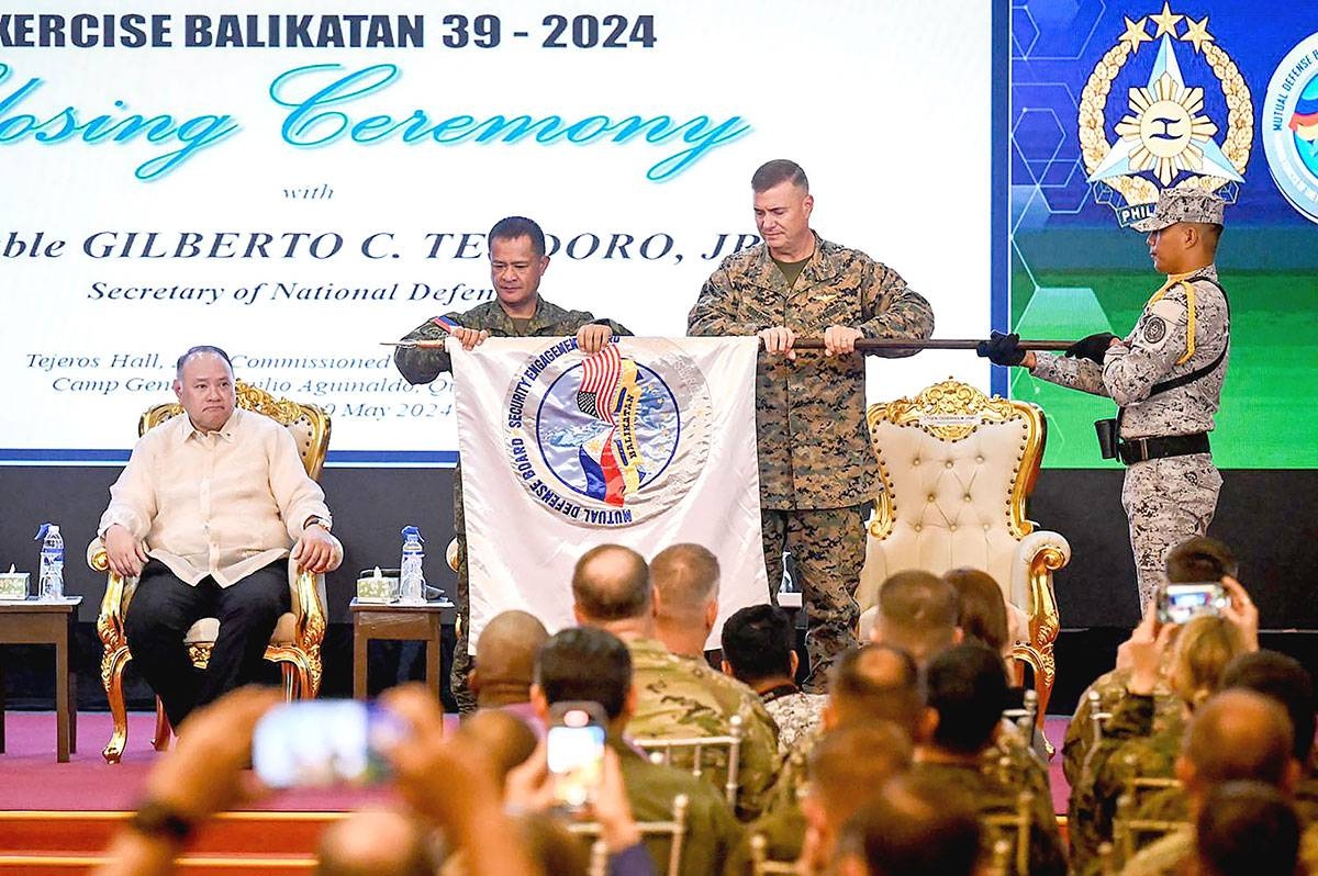 FURLING THE FLAG Philippine Army Maj. Gen. and Balikatan Director Marvin Licudine (second from left) and Commander of the US First Marine Expeditionary Force Lt. Gen. Michael Cederholm (second from right) furl the Balikatan (shoulder-to-shoulder) flag during the closing ceremony of the US-Philippines Balikatan joint military exercise at Camp Aguinaldo in Quezon City on May 10, 2024. Also in photo is Defense Secretary Gilbert Teodoro. JAM STA ROSA / AFP